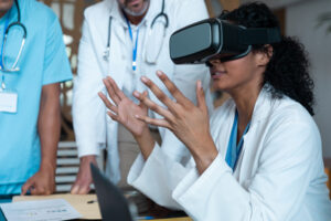 Diverse male and female doctors wearing face masks sitting at table and using vr glasses. medicine, health and healthcare services.