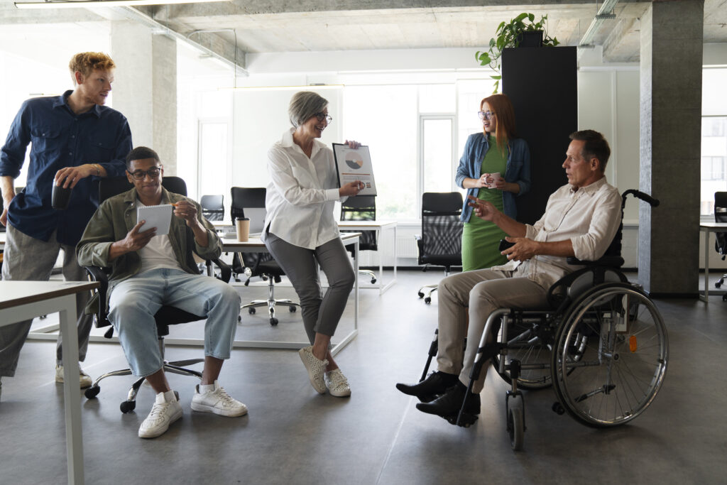 man in a wheel chair working on a project with colleagues at work