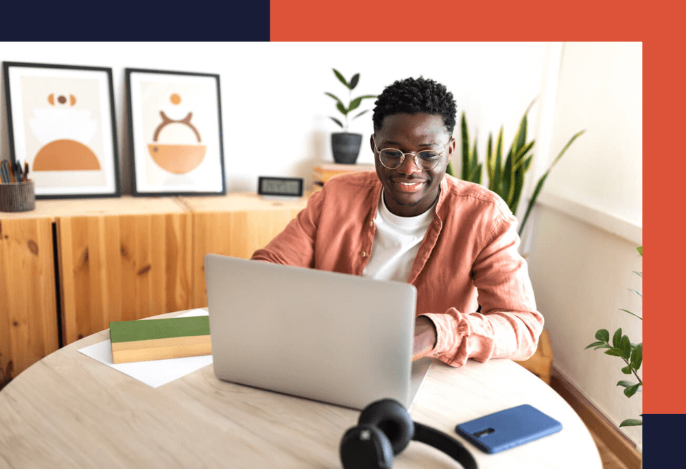 Happy black male university student studying at home using laptop. Education and technology