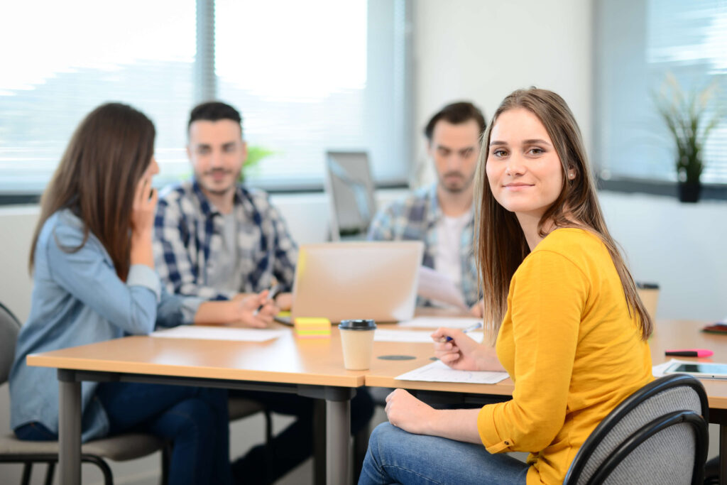 portrait of young woman in casual wear working in a creative business startup company office with coworker people in background