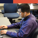 Person sitting in front of a computer using assistive devices to work,.