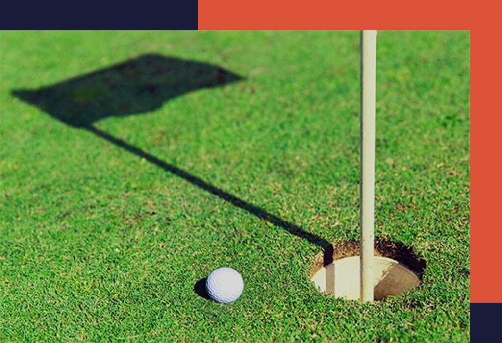 golf ball on the green next to hole with a shadow of the flag