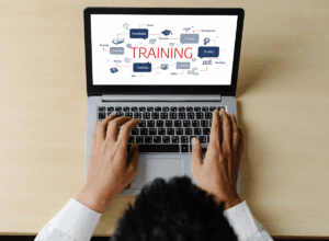 Man typing on laptop screen that reads: training, development, and learning. 